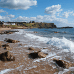 Seaglass beach with rocks, waves, and coastal cliffs in the background, ideal for seaglass hunting a.
